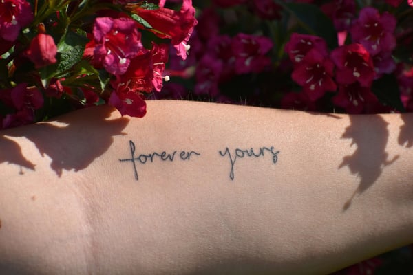 Pessoa mostrando tatuagem com frase no braço