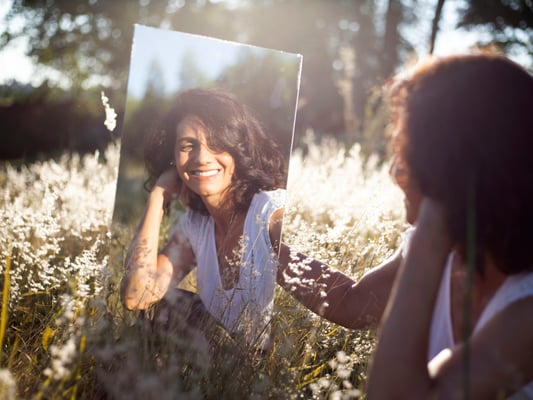 Mulher sorrindo com confiança olhando para o espelho