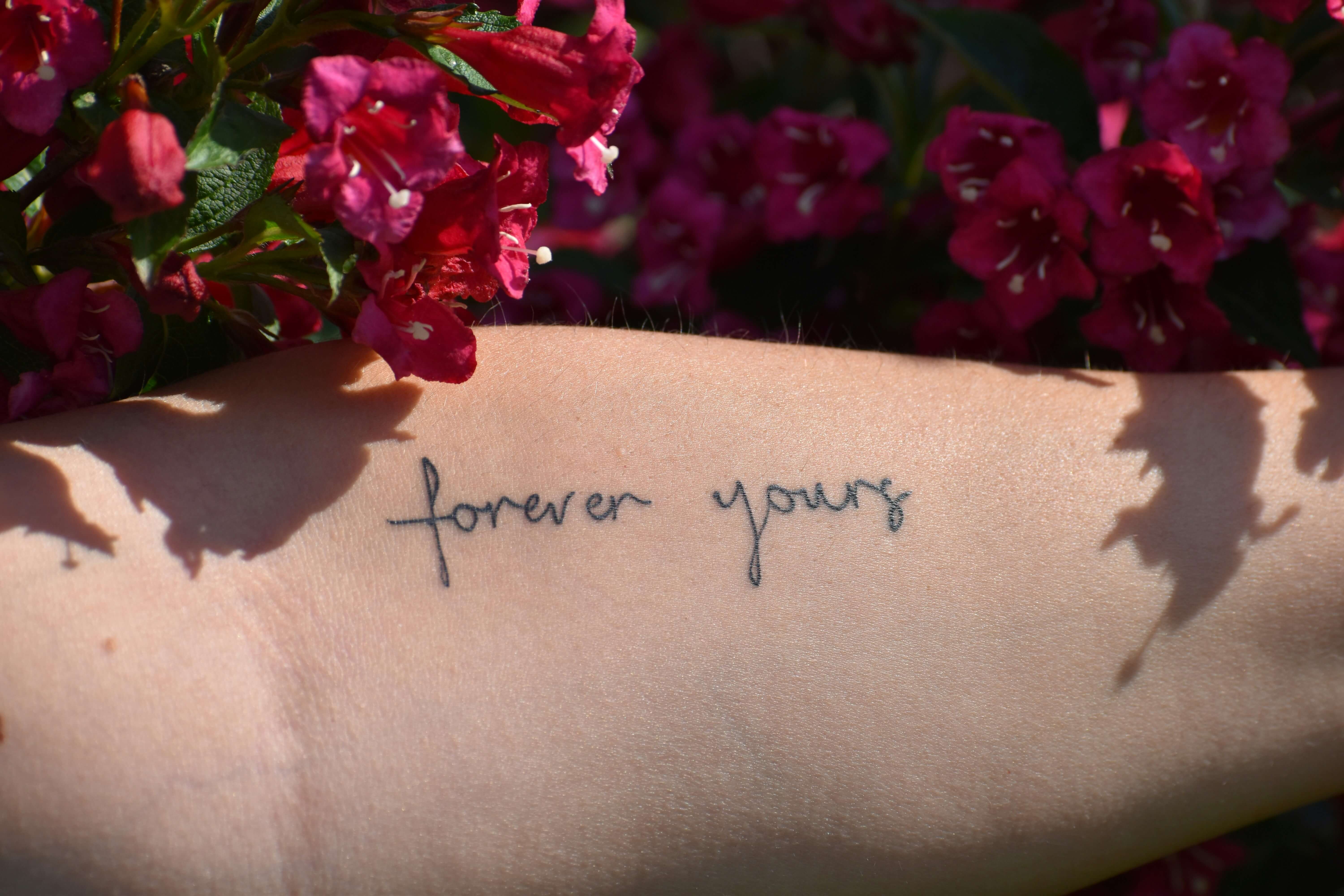 Pessoa mostrando tatuagem com frase no braço