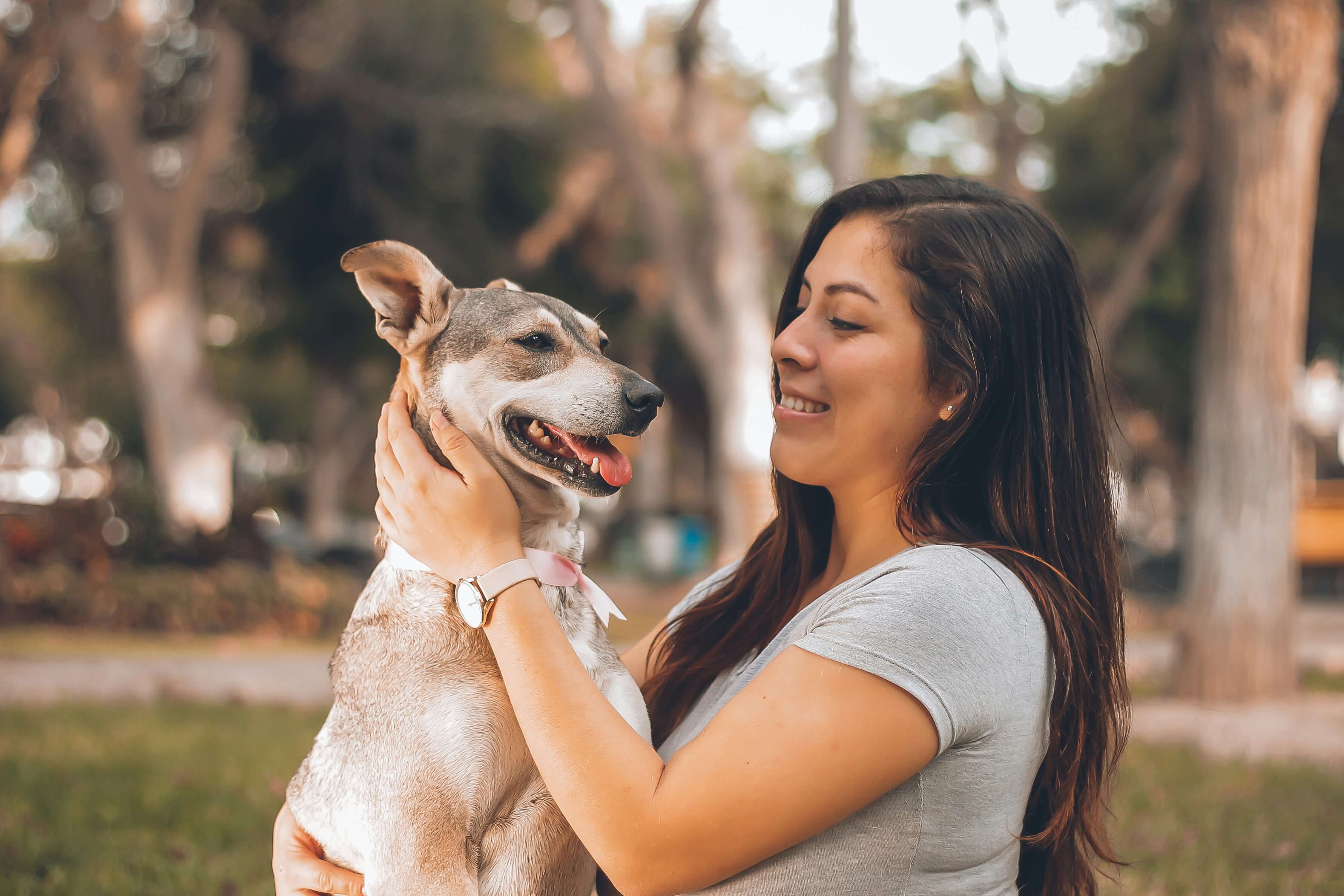 Pessoa sorrindo abraçada ao seu cachorro